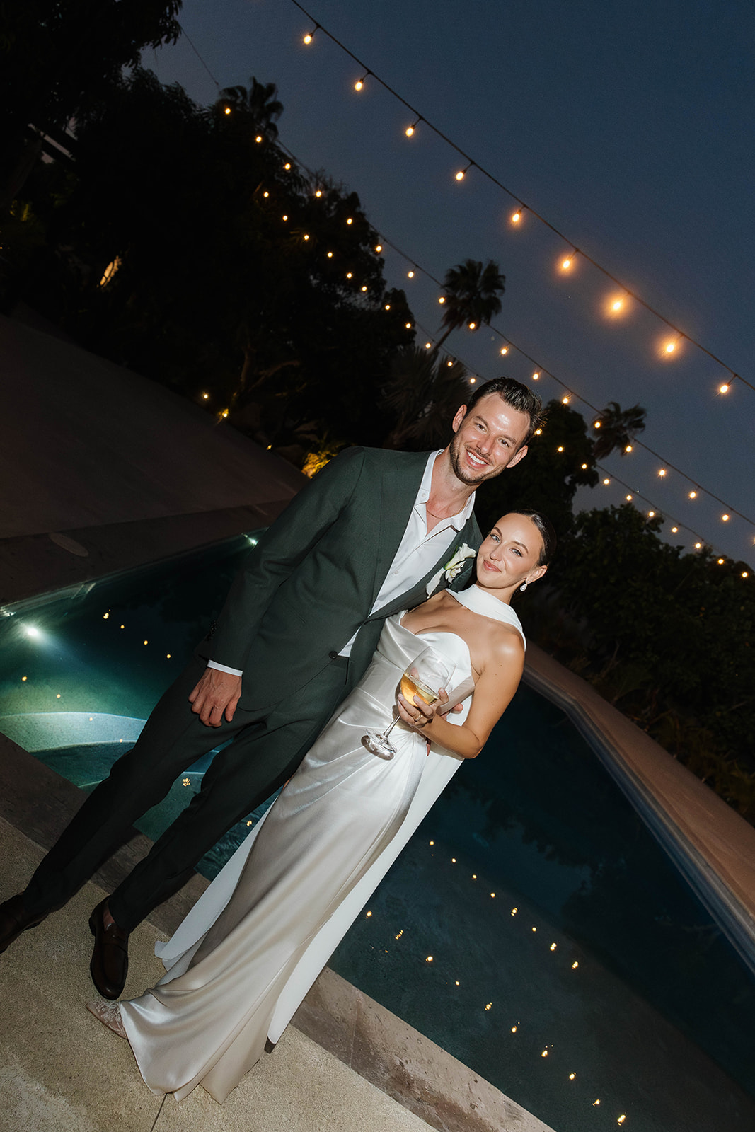 flash wedding photo of the bride and groom in front of the pool at their cabo wedding venue