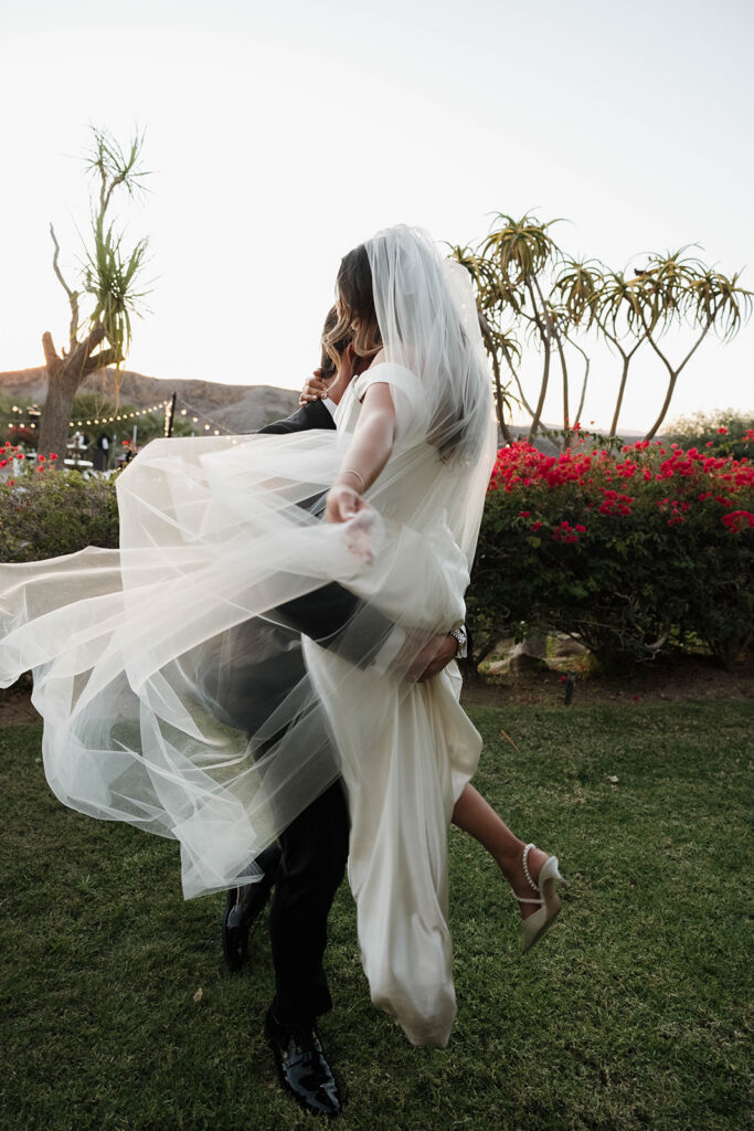 bride and groom twirling around in the lush gardens during their hummingbird nest ranch wedding day