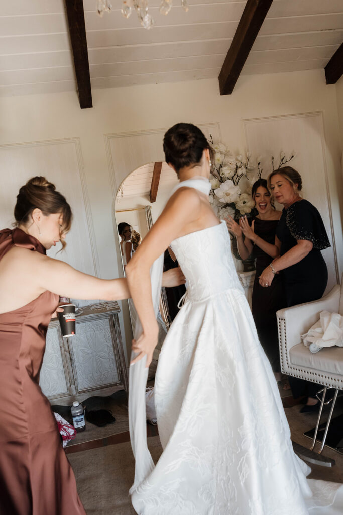 friend helping bride into her dress