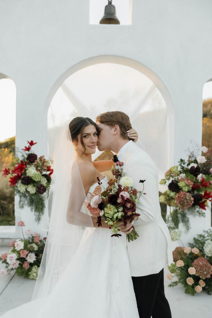 groom kissing bride on the cheek at the wedding cereremony site at jeune perche