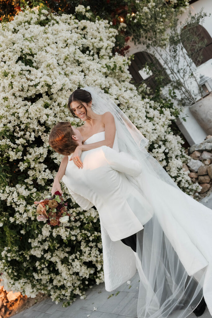 bride and groom twirling around in front of a floral covered wall in jeune perche estate
