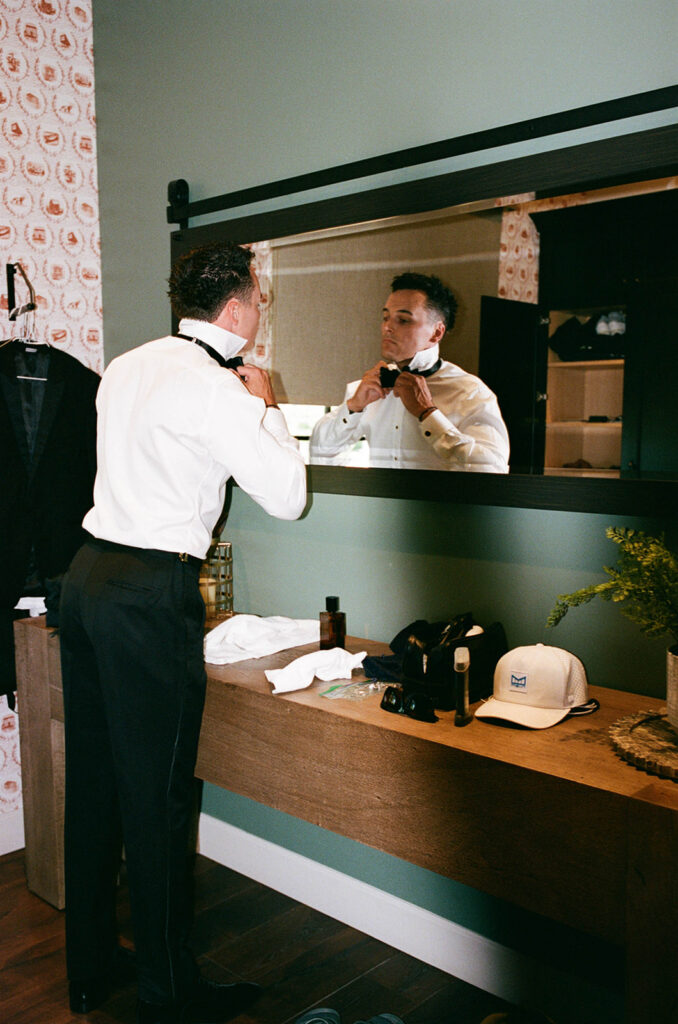 groom getting ready in front of a mirror
