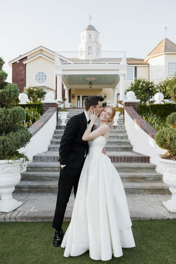 bride and groom kissing in front of their morgan estate wedding venue