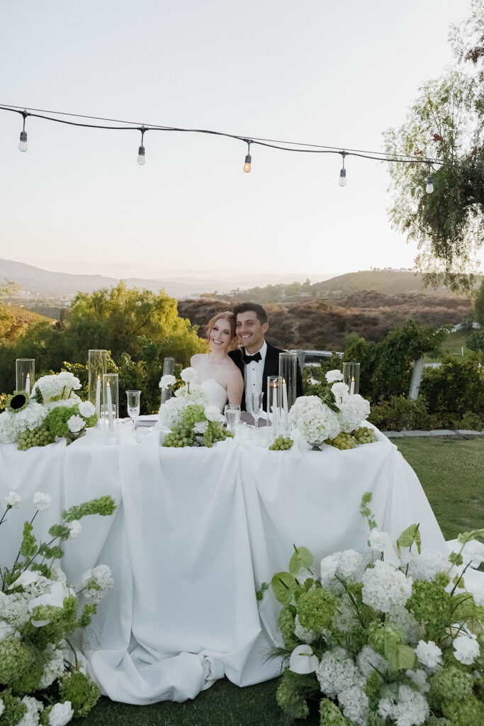 bride and groom sitting at their sweetheart table during their morgan estate wedding reception