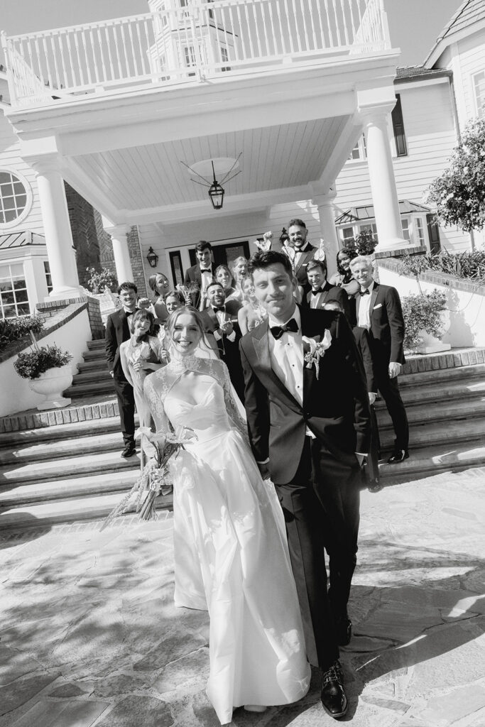 happy wedding couple with their wedding party in front of Morgan Estate