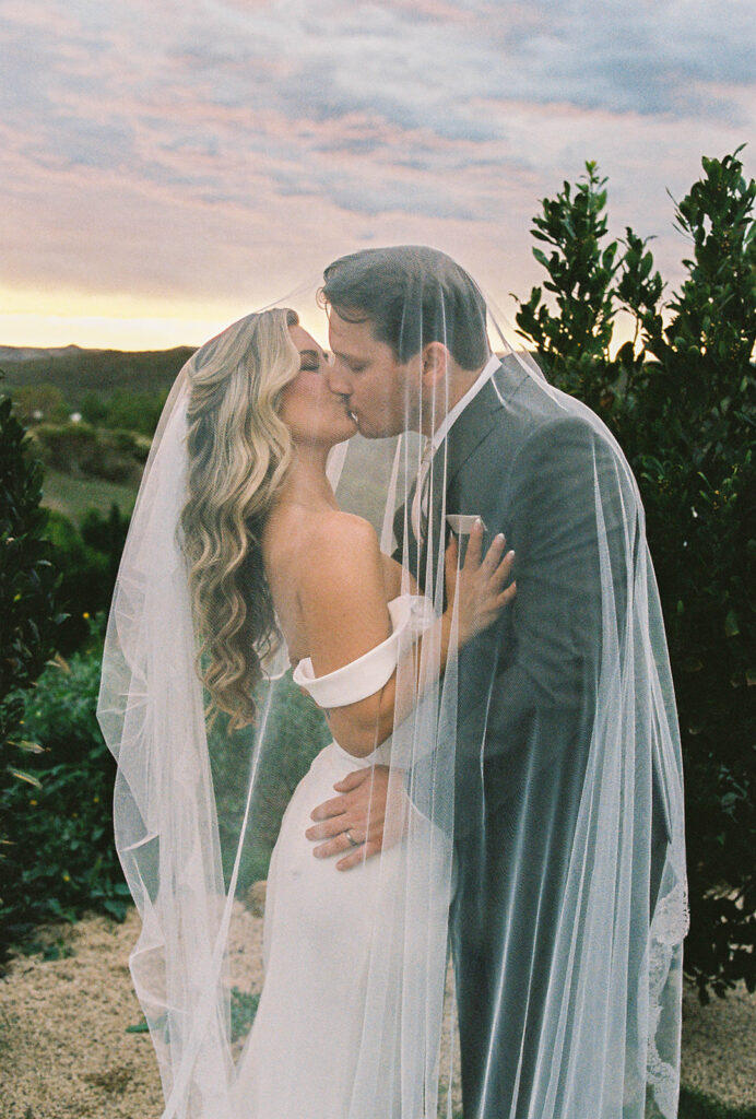 bride and groom kissing surrounded by rolling hills at their california estate wedding venue