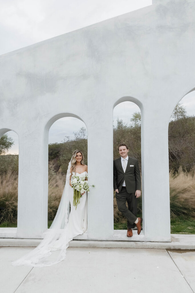 bride and groom posing at a modern white arch during their california estate wedding at jeune perche