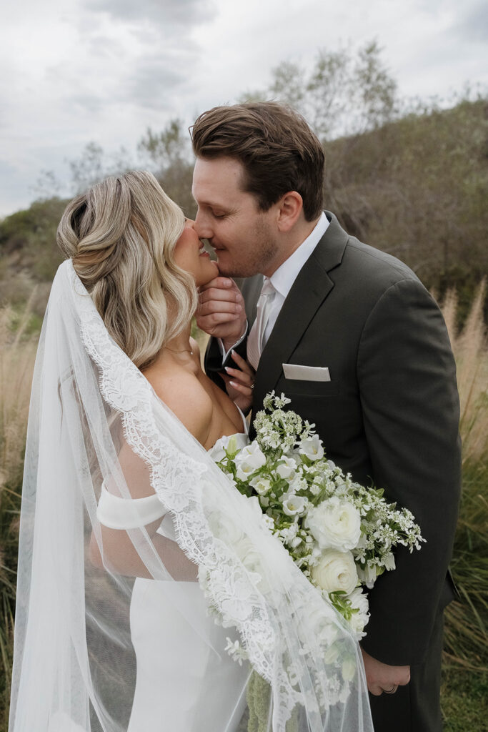bride and groom kissing surrounded by rolling hills at their california estate wedding venue