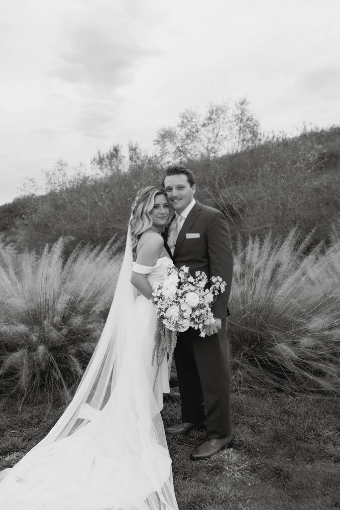 bride and groom posing in front of a lush greenery at jeune perche