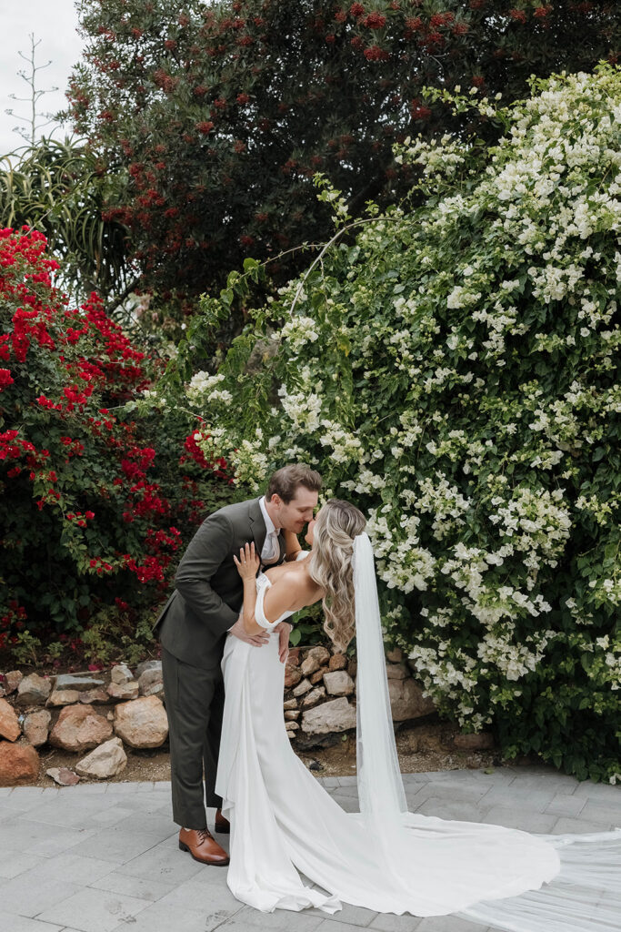 bride and groom posing in front of a lush flower bush at jeune perche
