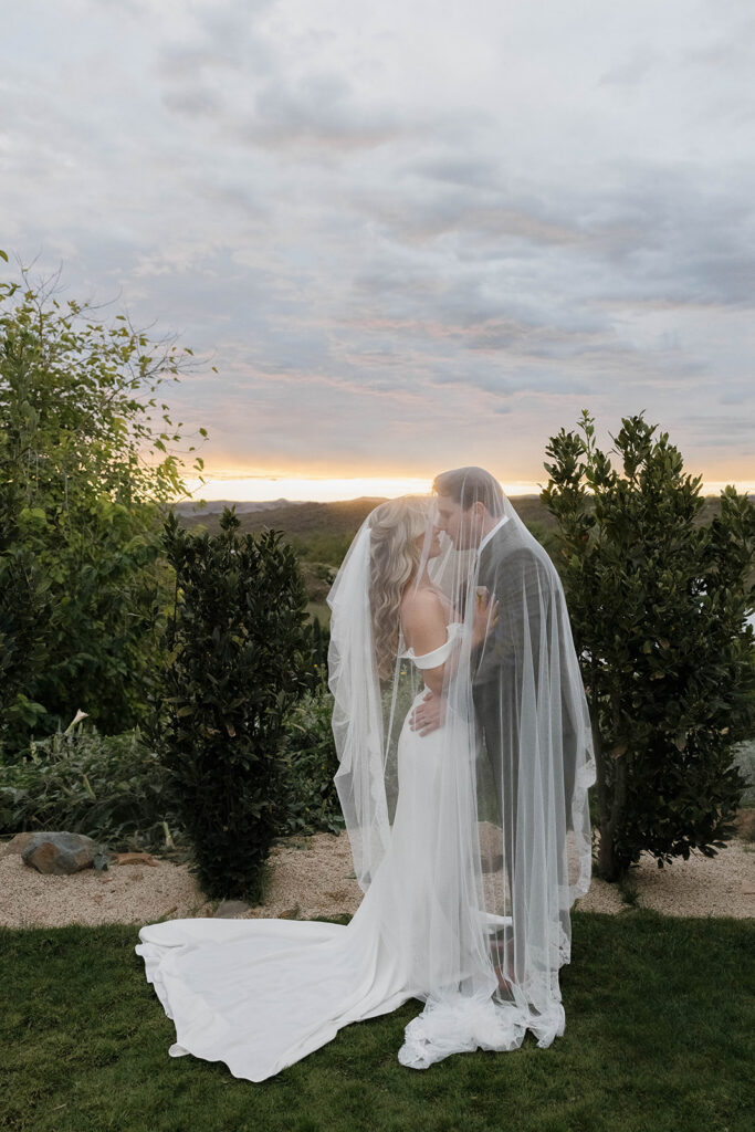 bride and groom kissing surrounded by rolling hills at their california estate wedding venue