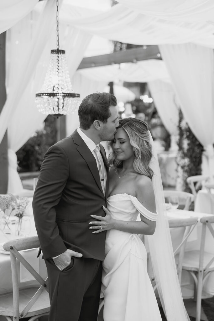 groom kissing his bride on the forehead at the romantic outdoor reception space during their california estate wedding at jeune perche