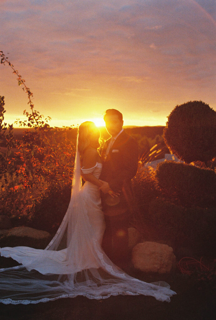 bride and groom kissing surrounded by rolling hills during golden hour at their california estate wedding venue
