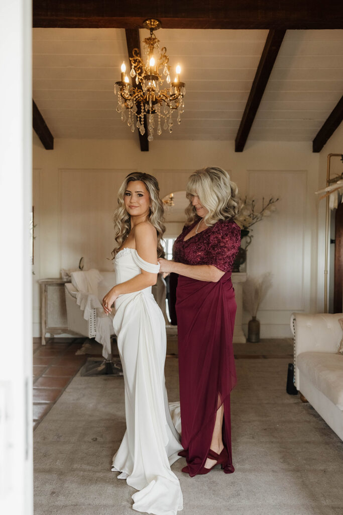 mom helping bride into her dress
