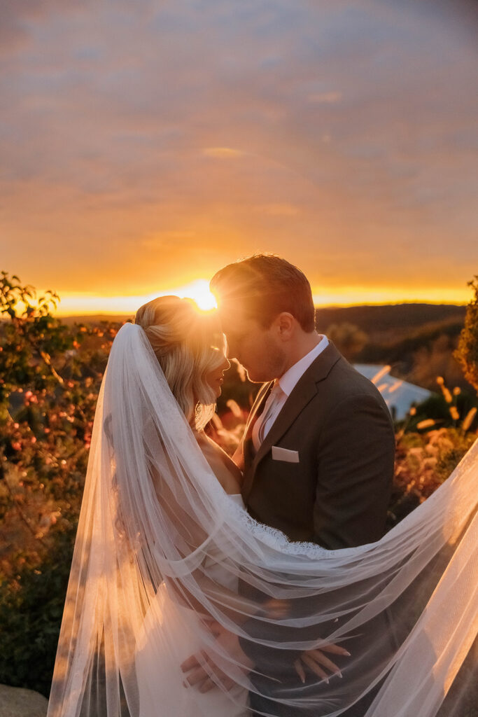 bride and groom kissing surrounded by rolling hills during golden hour at their california estate wedding venue