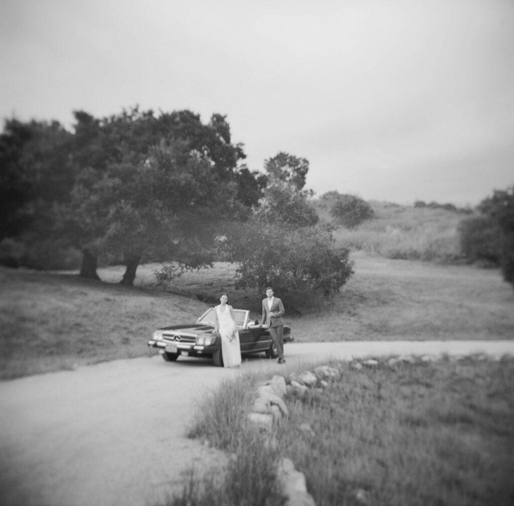 bride and groom posing with a vintage car during their ojai wedding