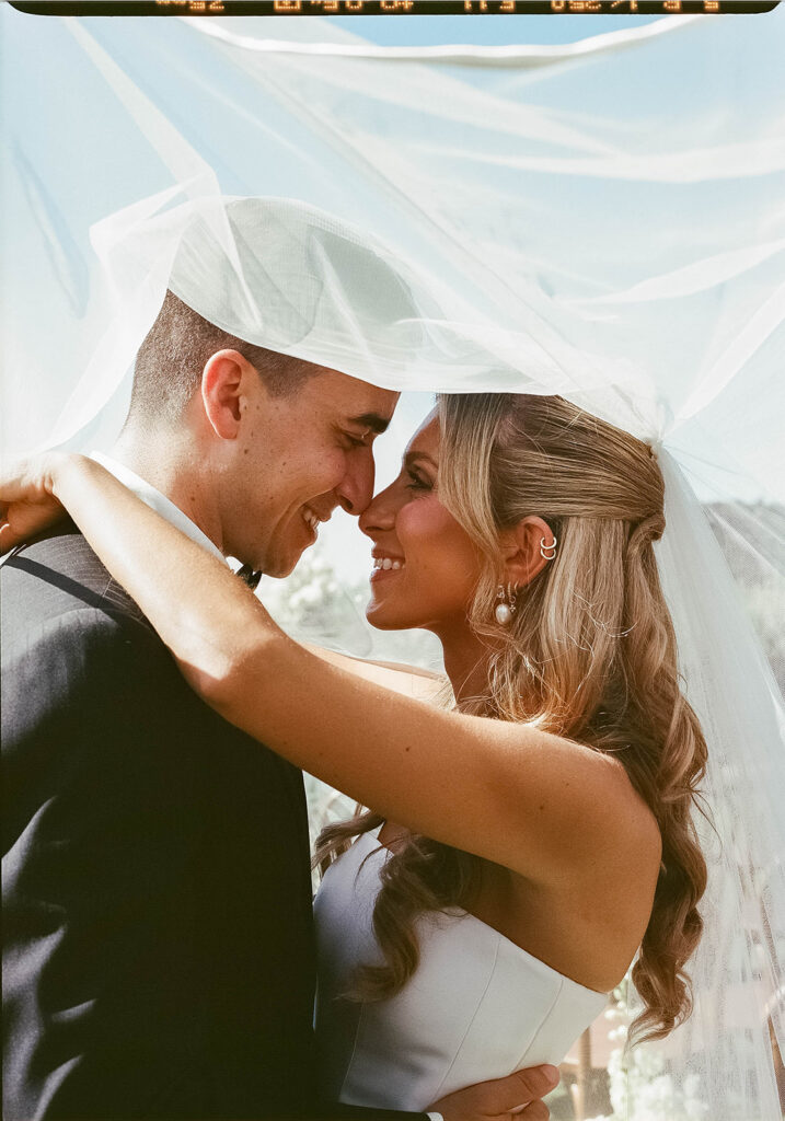 smiley bride and groom under veil during their cielo farms malibu wedding day