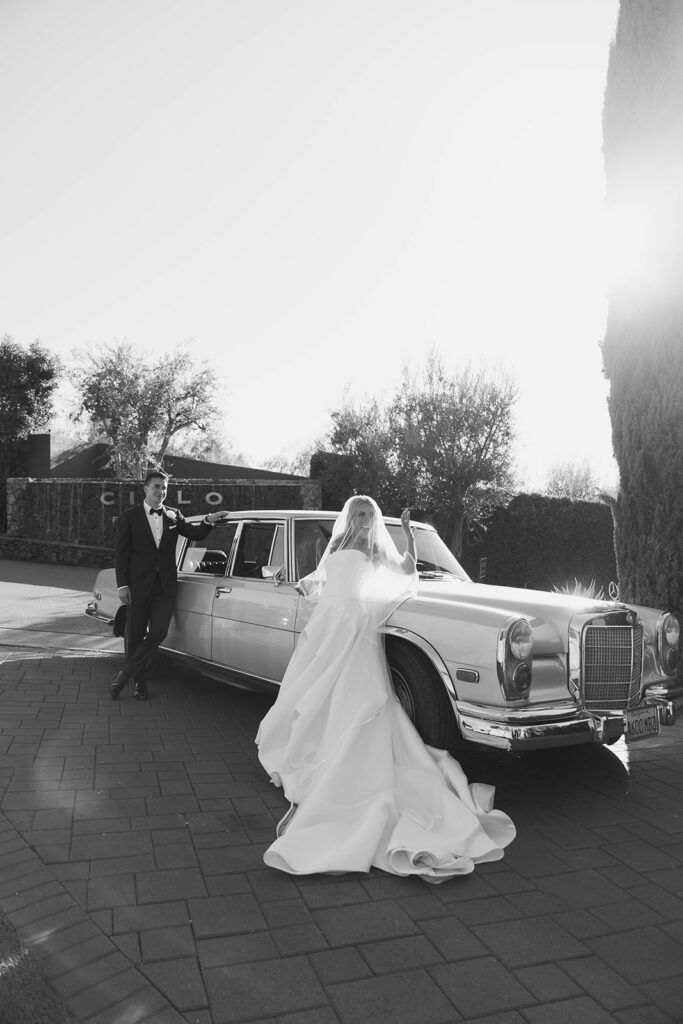 smiley bride and groom in front of a vintage car during their malibu wedding day at cielo farms